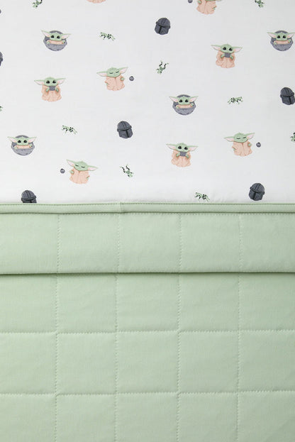 Close up of the light green quilted backing and the smooth printed top layer shown on the Toddler Blanket in Grogu™ 1.0