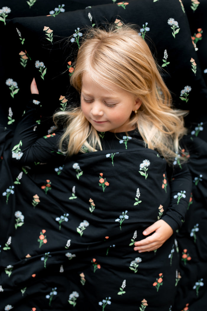 Girl sleeping on Toddler Pillowcase in Midnight Wildflower print lying under similar print Toddler blanket and sheets