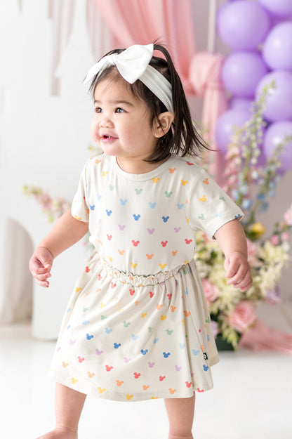 toddler wearing mickey mouse skort and matching tee with colorful flowers and balloons in background