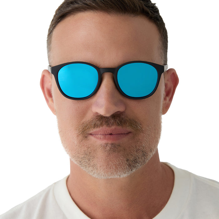 on model - male wearing diff sport featuring the volley round sunglasses with a matte black frame and blue mirror polarized lenses front view