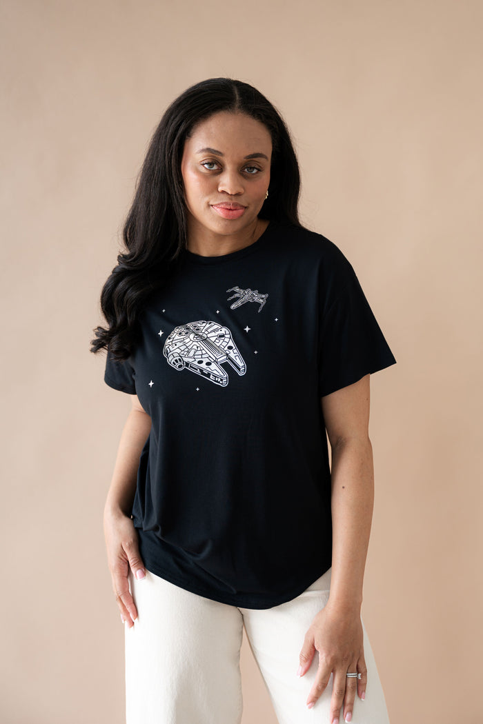 Female posing wearing the Women's Graphic Tee in Millennium Falcon™ with cream pants