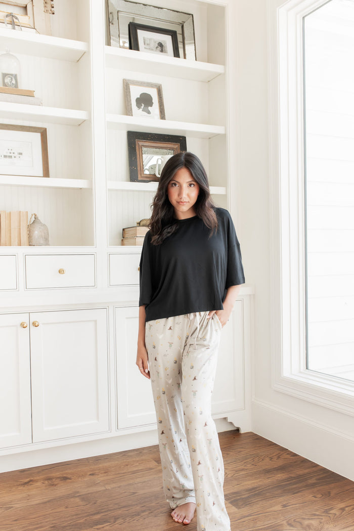 Model standing in front of a wall wearing the Women's Lounge Pants with Harry Potter pattern with a black oversized short t-shirt.