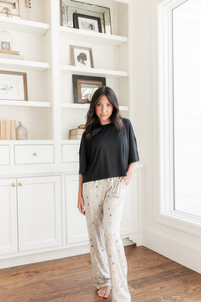 Model standing in front of a wall wearing the Women's Lounge Pants with Harry Potter pattern with a black oversized short t-shirt.