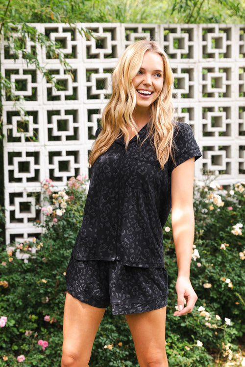 Close up of smiling female wearing the Women’s Short Sleeve Pajama Set in Midnight Leopard