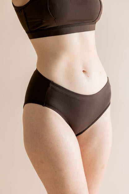 Person wearing a brown bra and panties set on a beige background