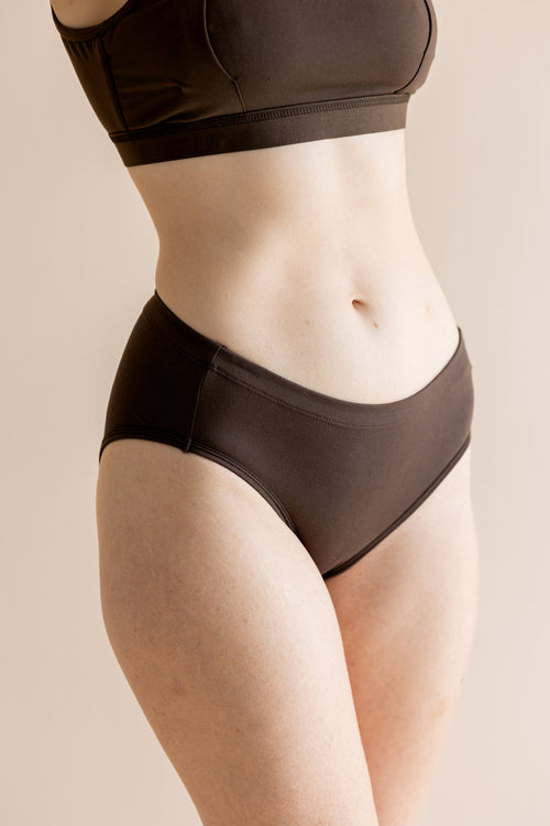 Person wearing a brown bra and panties set on a beige background