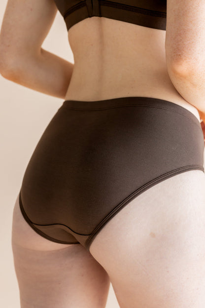 Person wearing brown underwear on a beige background