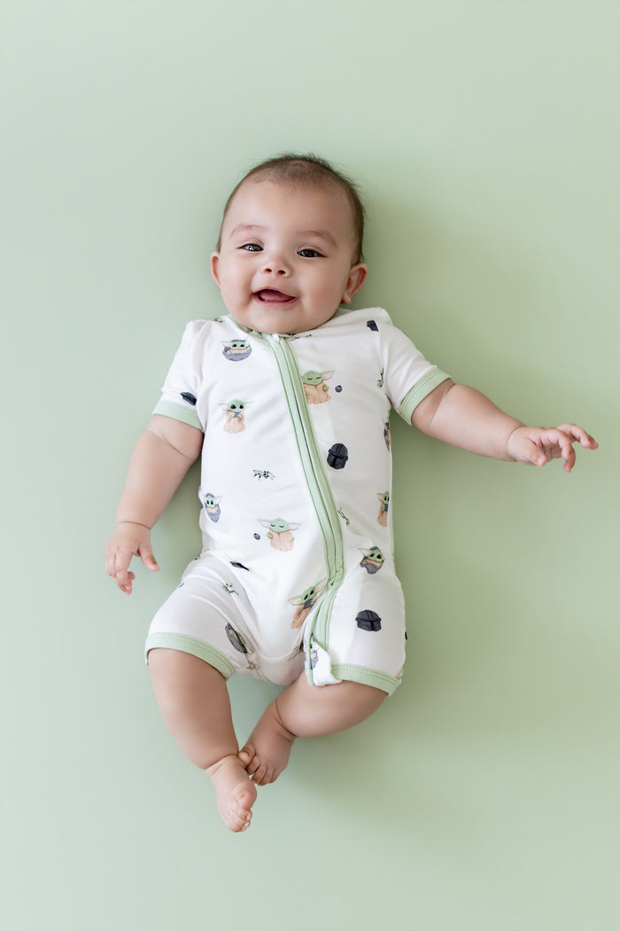 Smiling infant wearing the Zipper Shortall Romper in Grogu™